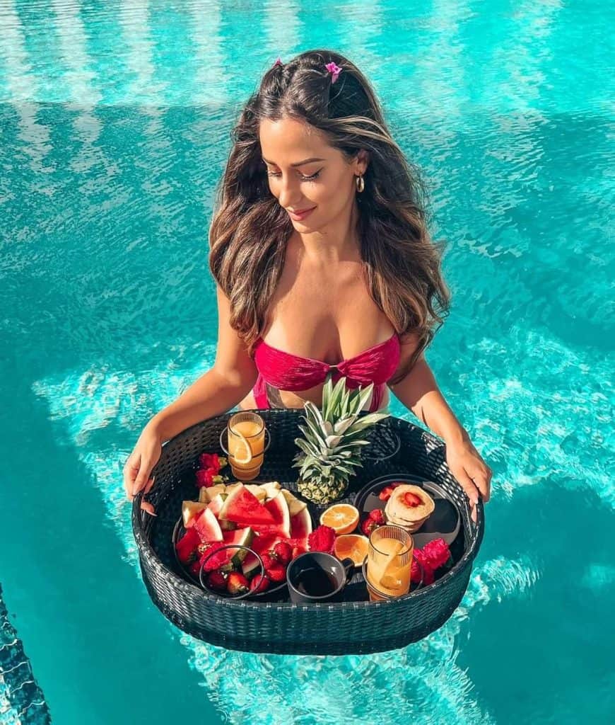 a woman holding a basket of fruit in a pool